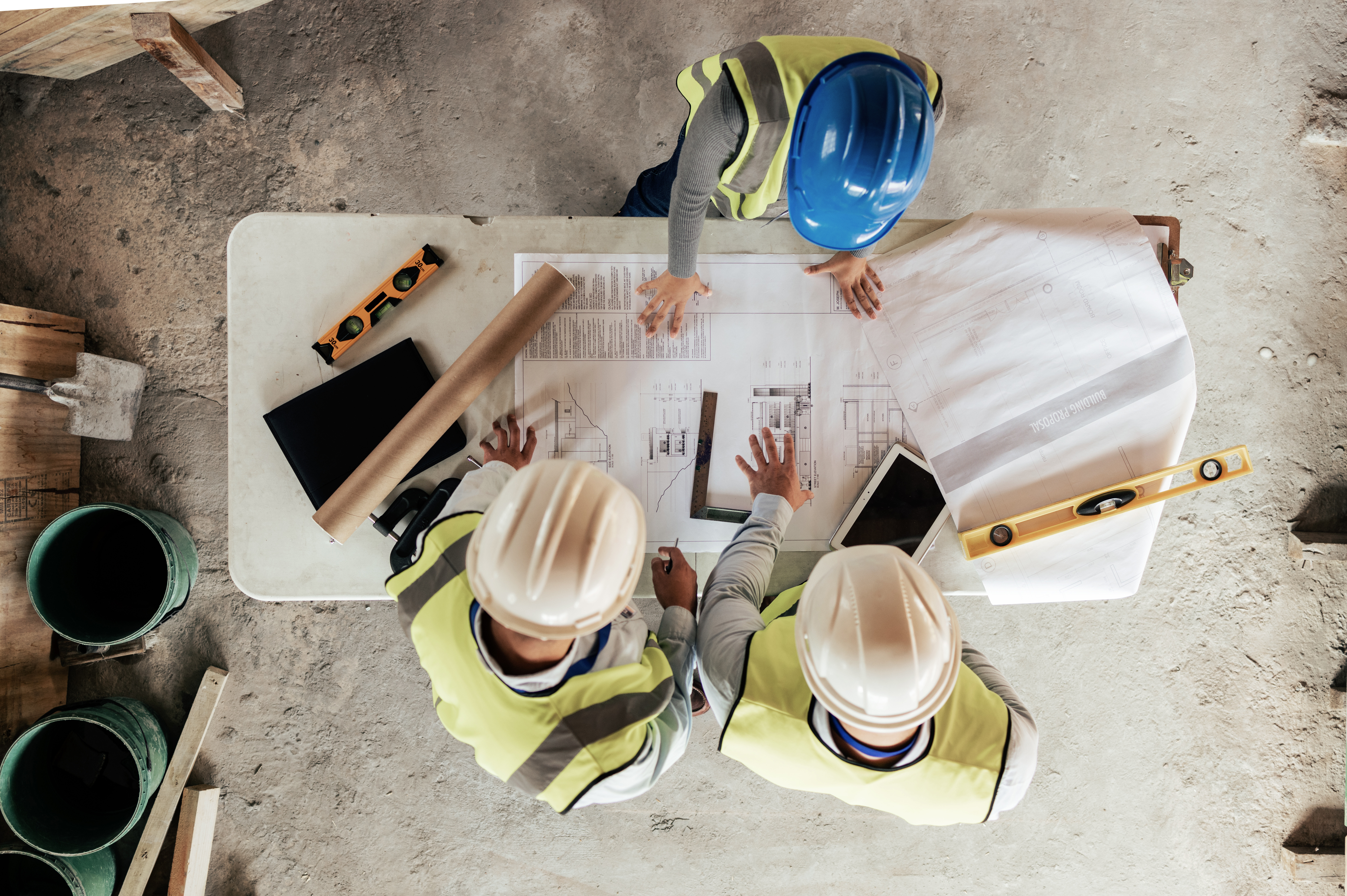 Berthold-Bau: Professionelle Baustellenplanung in Lauta Drei Bauarbeiter in Sicherheitskleidung besprechen Baupläne auf der Baustelle, zeigt Koordination von Berthold-Bau in Lauta.